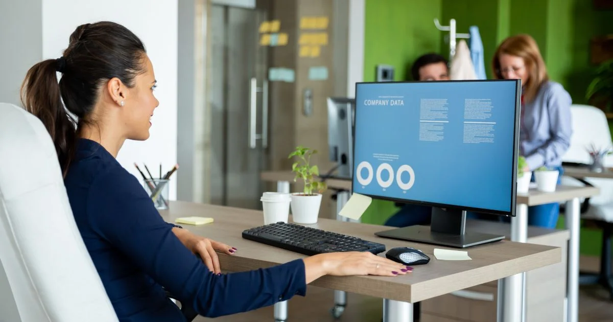 A woman sitting at an office desk, reviewing company data